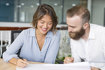 Glückliches Paar übernimmt symbolisch den Wohnungsschlüssel von Immobilienmaklerin – der perfekte Moment beim Kauf einer möblierten Immobilie mit Mr. Lodge in München.